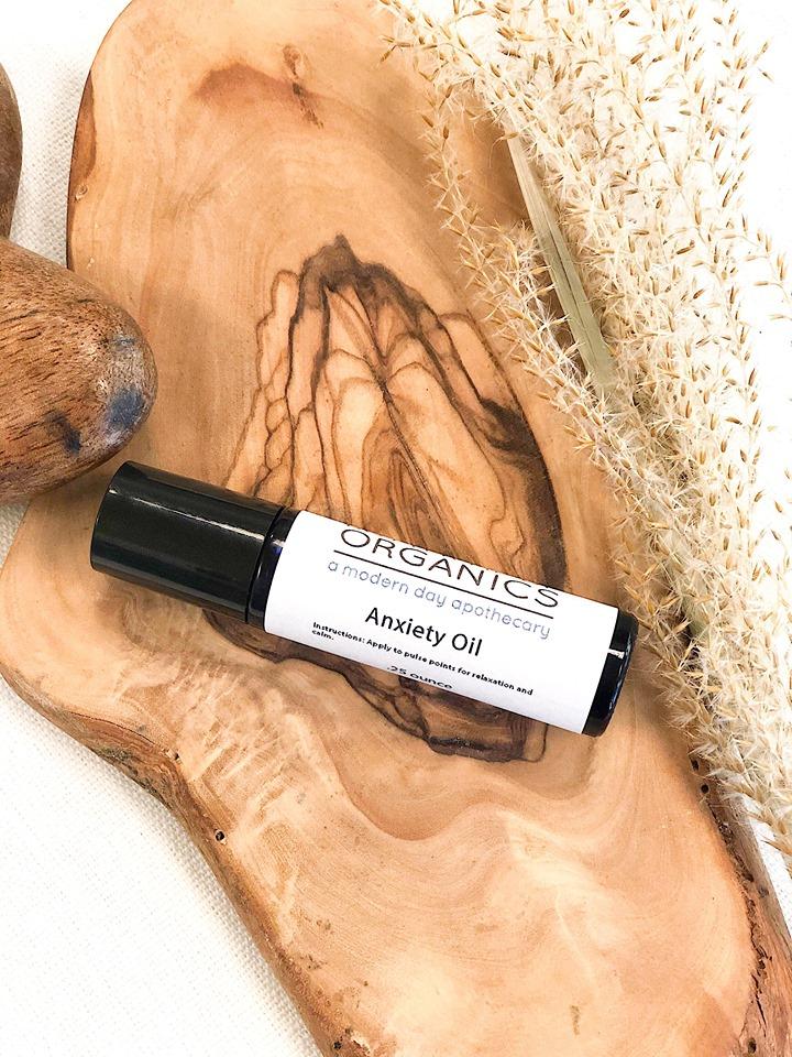 Roll-on bottle of 'Anxiety Oil' by Organics on a wooden surface with natural elements.